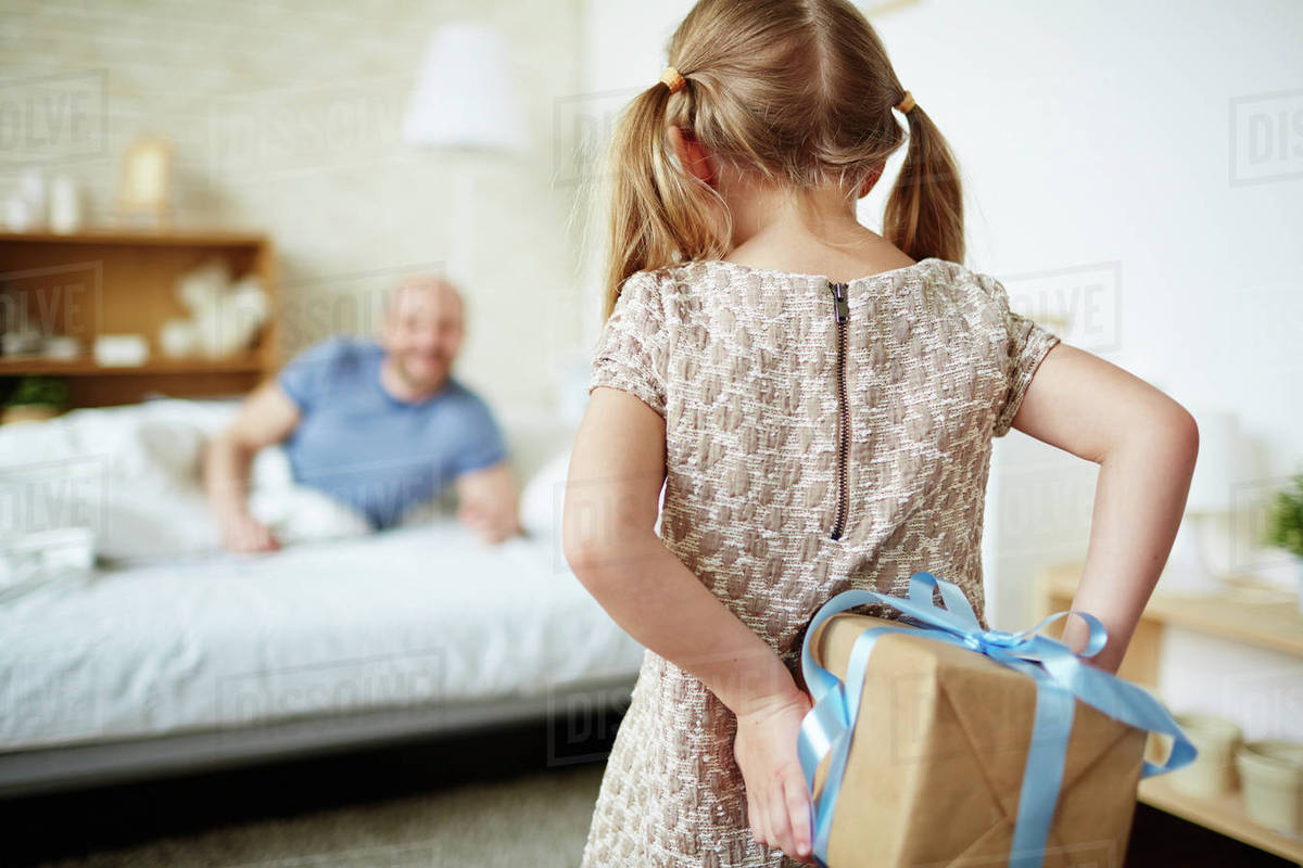 Little girl hiding giftbox behind back Stock Photo Dissolve