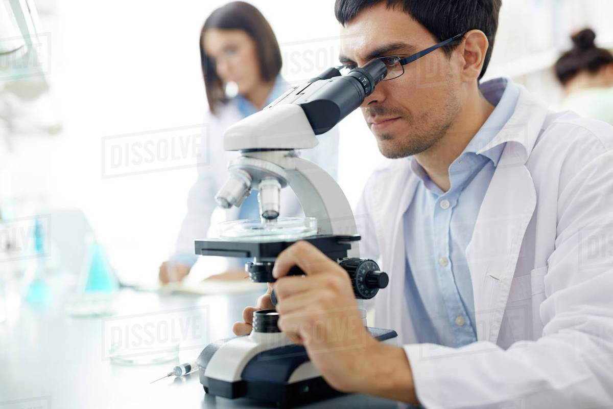 Young man looking in microscope in scientific laboratory Stock Photo