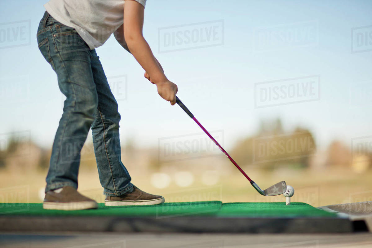 Young boy preparing to hit a golf ball off a tee. Stock Photo Dissolve