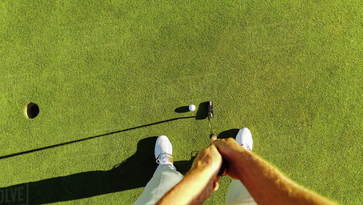 Pov shot of golf player at the putting green hitting ball into a hole