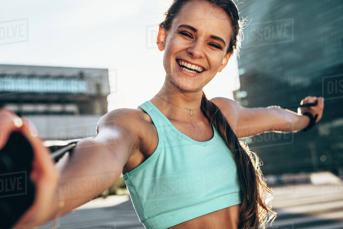 Athlete stretching arms with jump ropes. Sportswoman standing outdoors