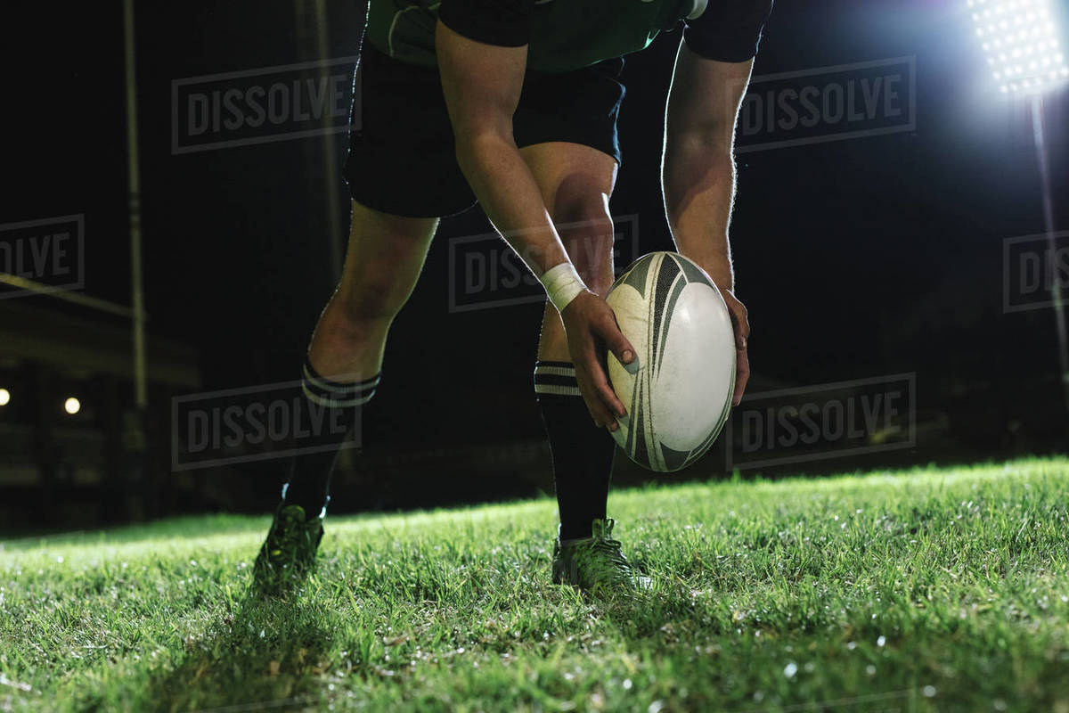 Rugby player dropping the ball to the ground for kicking as it touches