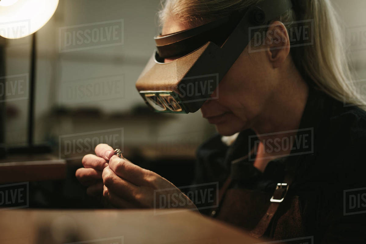 Close up of senior female jeweler examining a ring with magnifying
