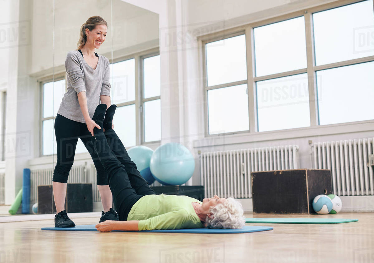 Personal trainer working with client on exercise mat at the gym