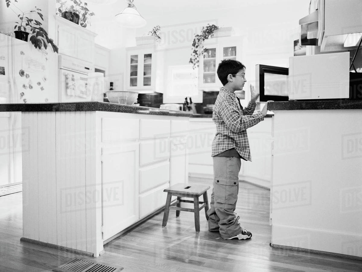 Young boy looking in microwave Stock Photo Dissolve