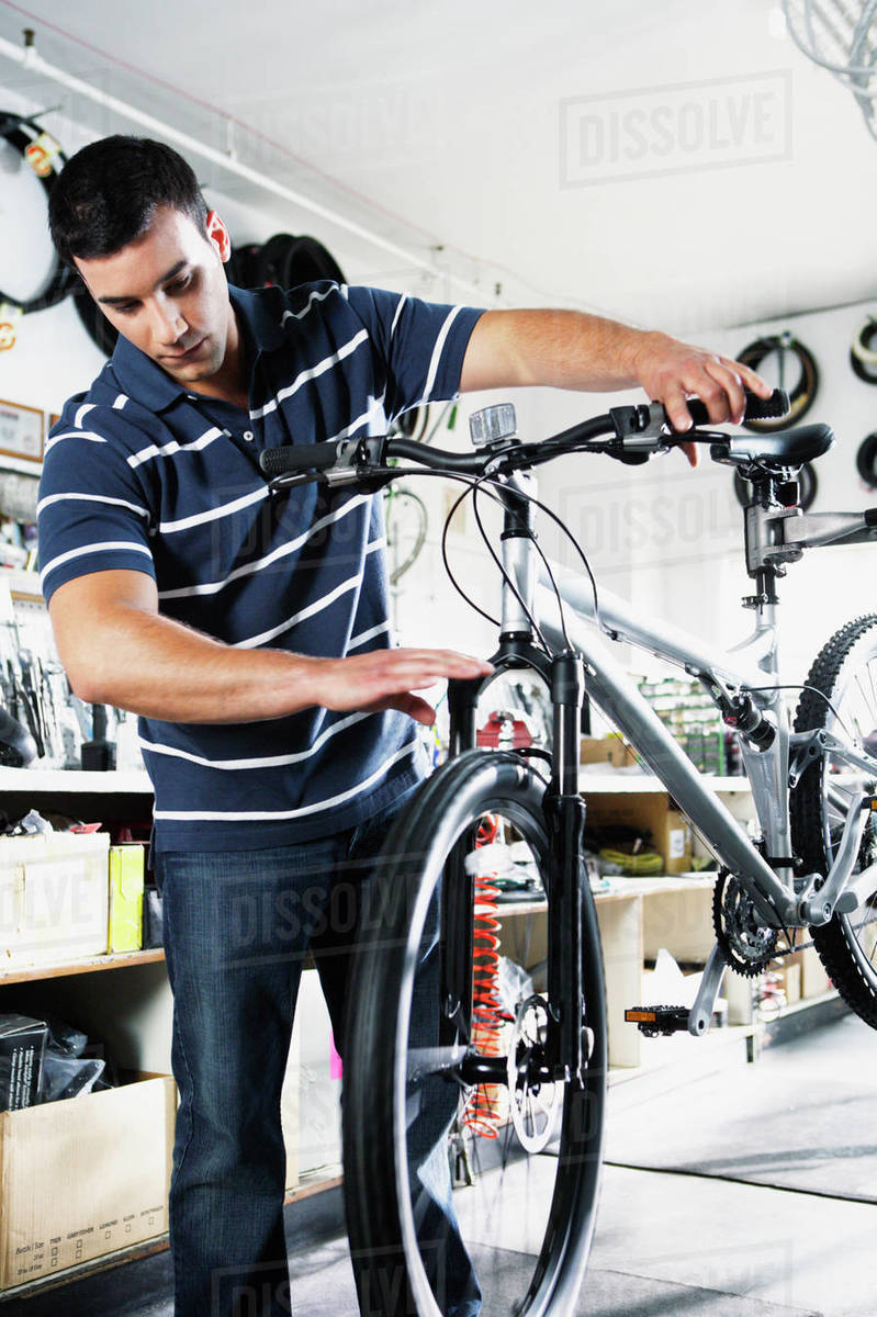 Man spinning wheel of bike in bike shop Stock Photo Dissolve