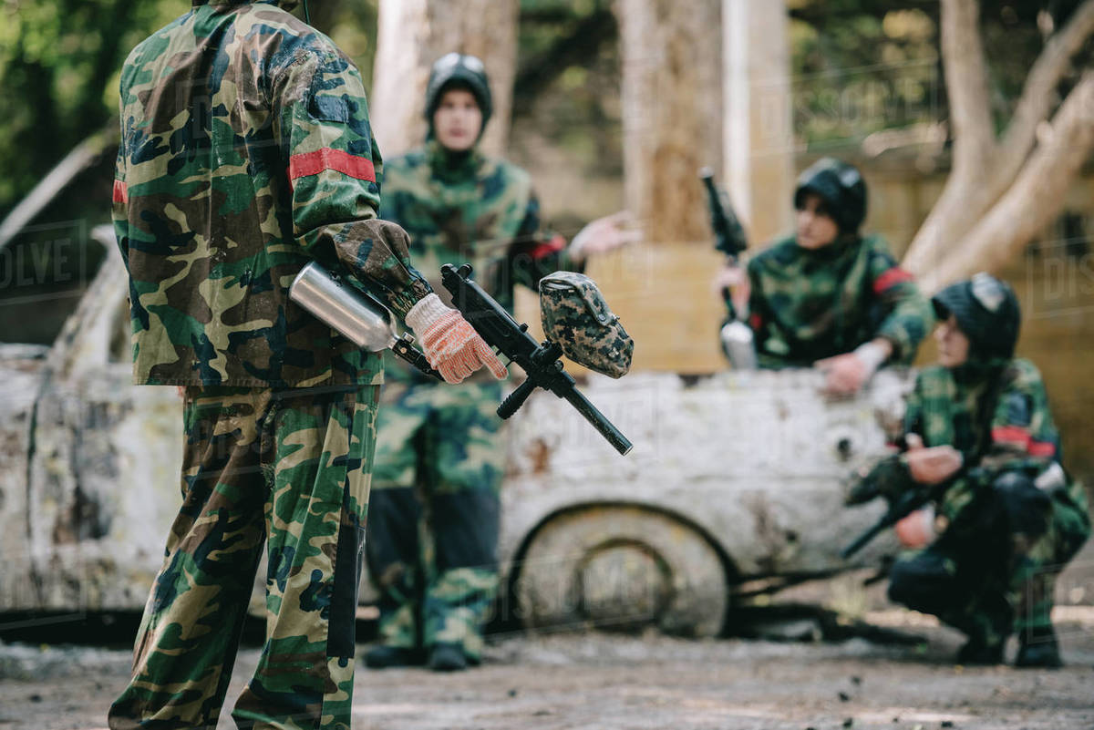 Cropped image of paintball team in camouflage uniform with marker guns