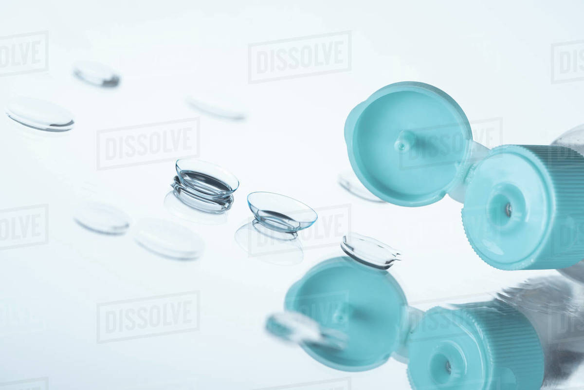 Close up view of contact eye lenses and bottle with cleansing liquid on