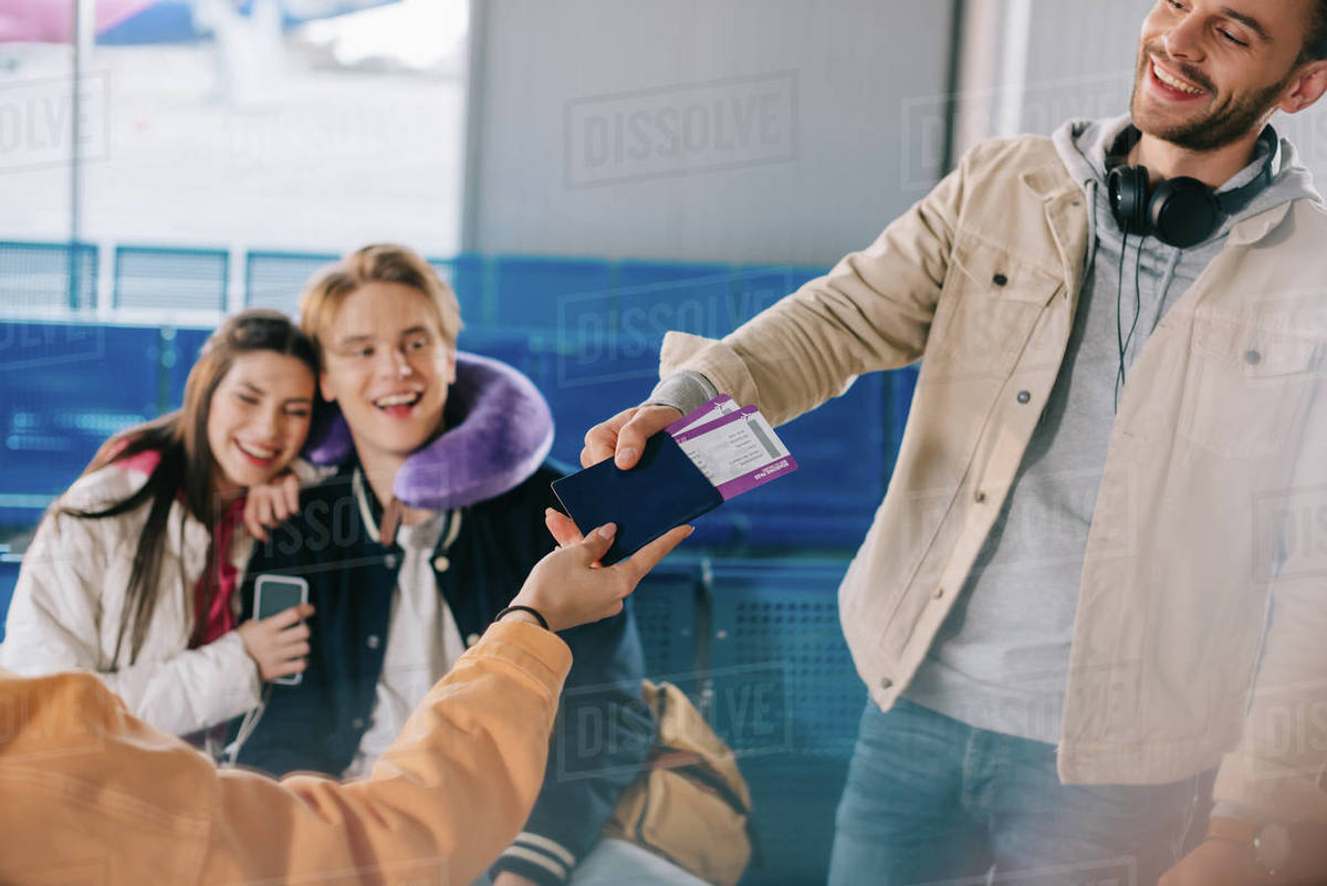 Cropped shot of friends holding passport with boarding passes while