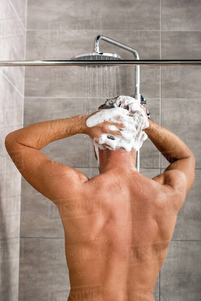 Back view of man washing hair with shampoo and taking shower Royalty-free stock photo