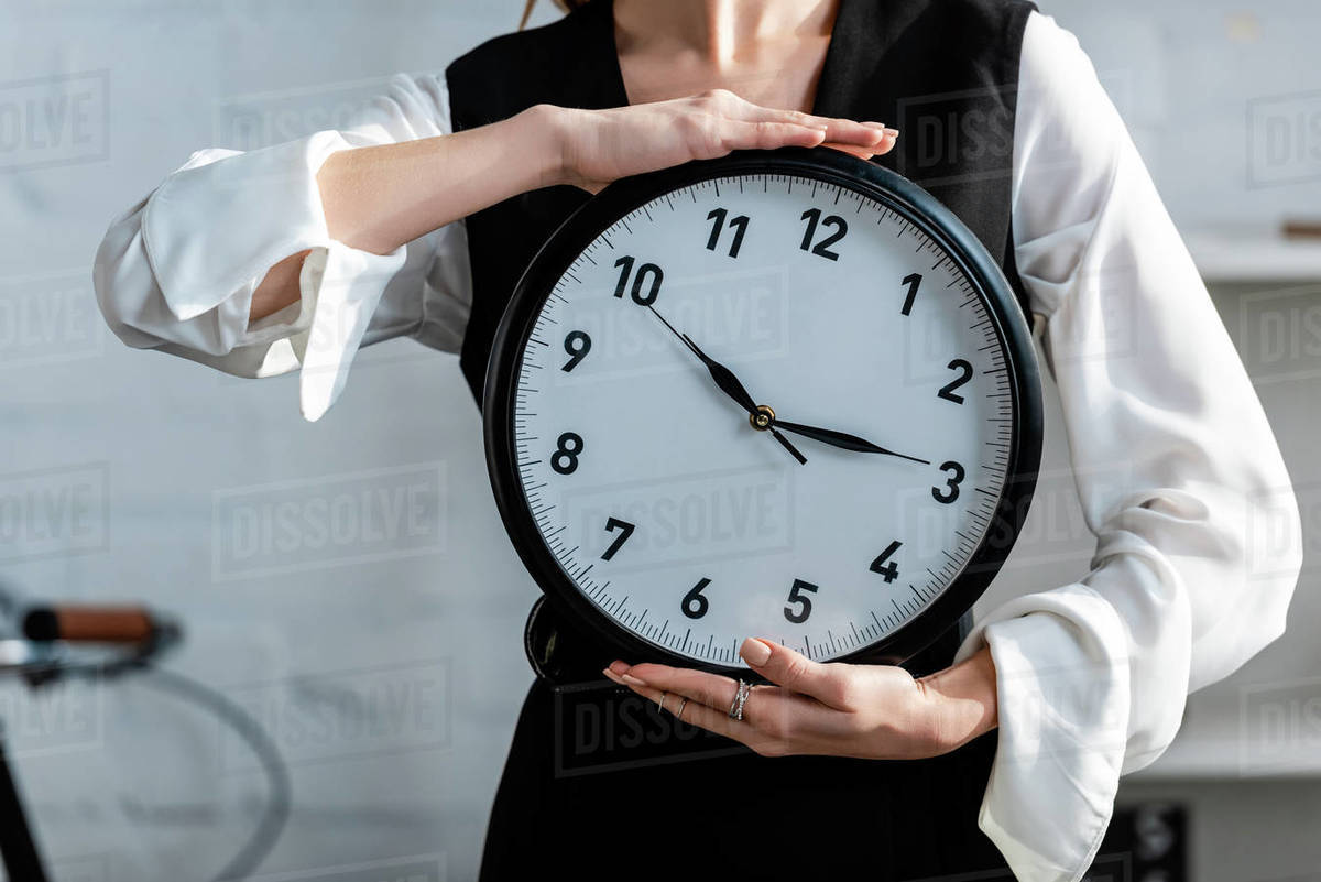 Cropped view of woman in formal wear holding clock in hands Stock