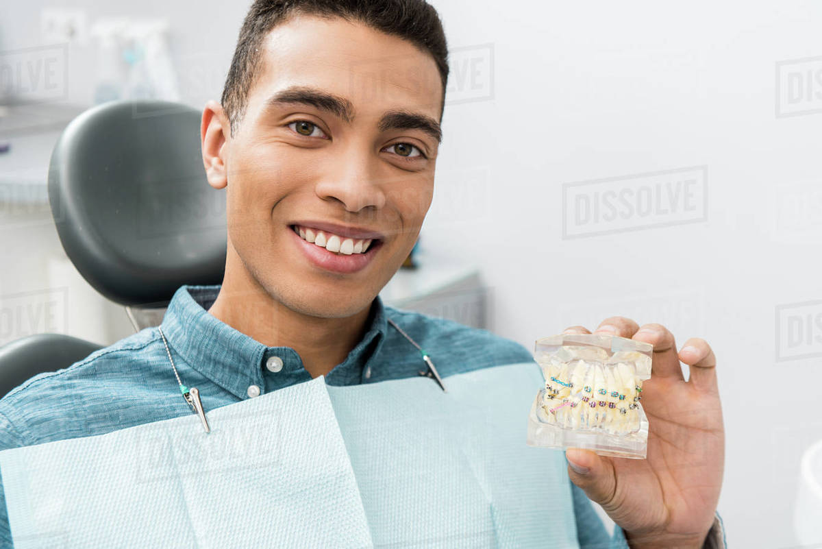 Handsome african american man holding dental jaw model with braces