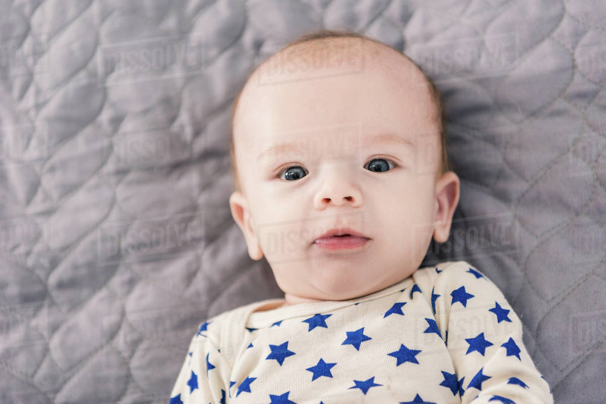 Overhead view of adorable little baby lying on grey blanket Stock