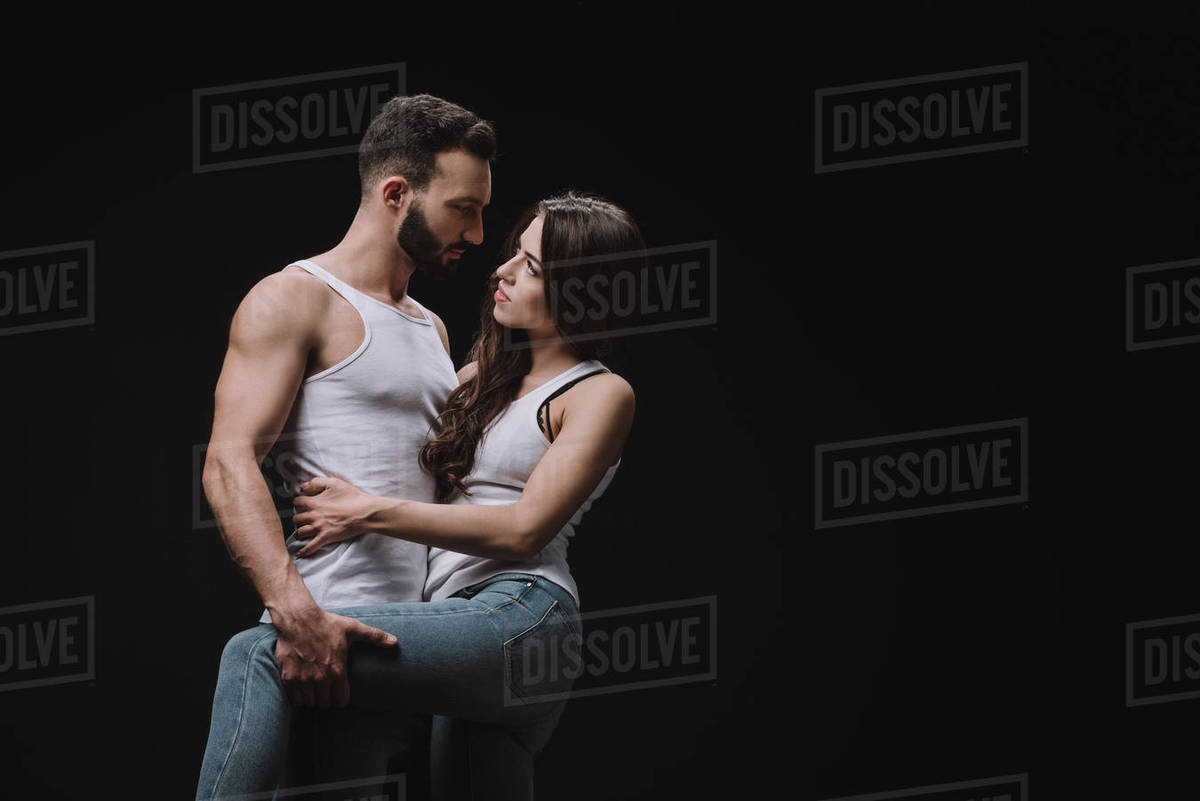 Handsome man hugging woman in white singlet isolated on black - Royalty ...