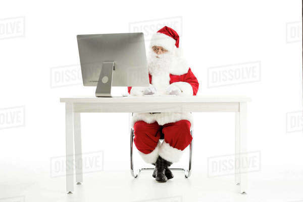 Santa Claus sitting at the desk and using computer isolated on white ...