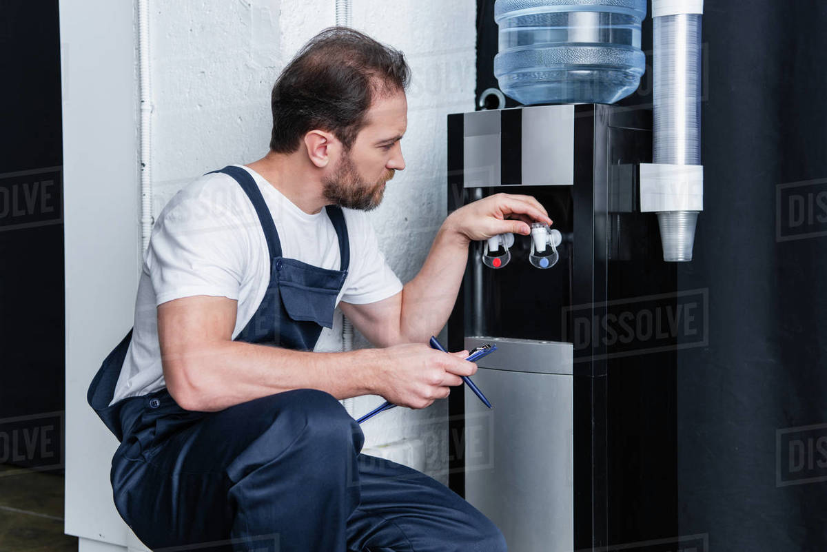 repairman with clipboard checking broken water cooler Stock Photo