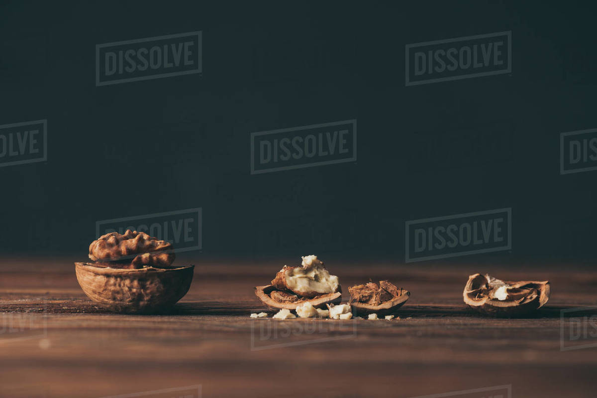 Cracked walnuts as dementia symbol on wooden table on black background