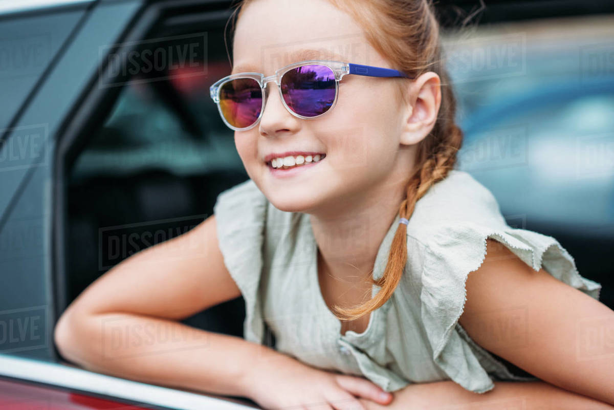 Adorable little girl in sunglasses looking out car window Stock Photo Dissolve
