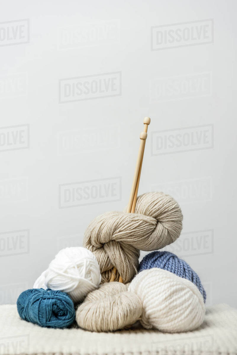 Close up view of knitting clews with knitting needles on grey backdrop
