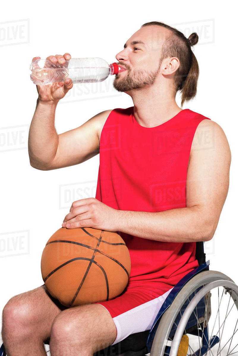 Disabled young basketball player sitting in wheelchair, holding a ball