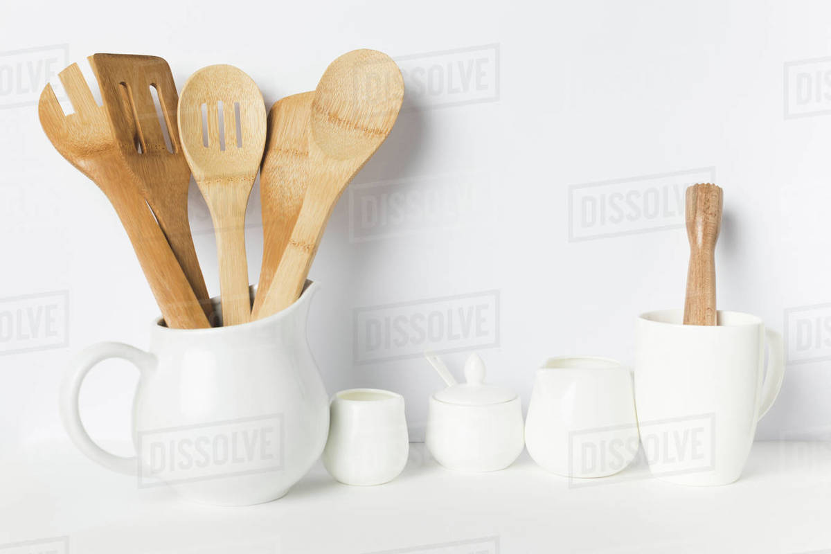 closeup view of wooden kitchen utensils in jug and ceramic cookware on