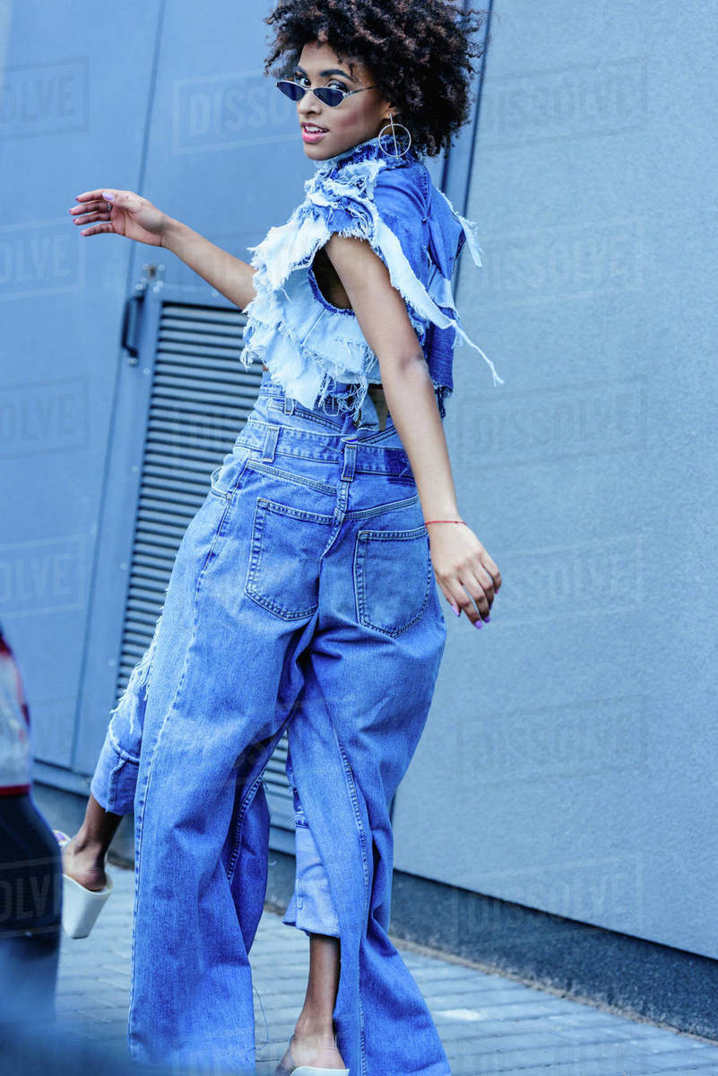 Fashionable African American girl in denim clothes walking on
