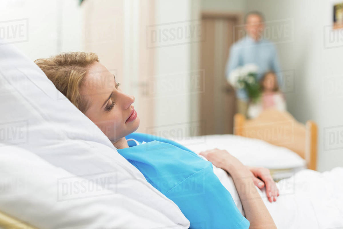 father and daughter bringing flowers to sick woman Stock Photo Dissolve