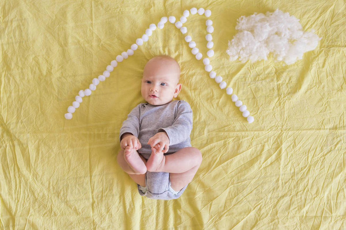 Top view of adorable child lying under house roof made of cotton balls