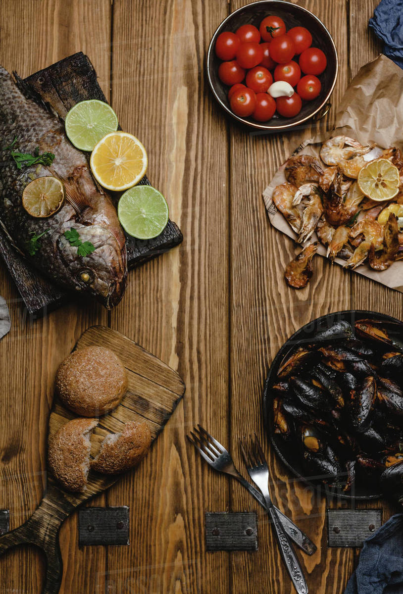 Top view of assorted seafood and baked fish with bread and tomatoes on