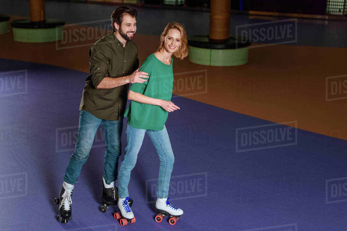 Young smiling couple skating together on roller rink Stock Photo