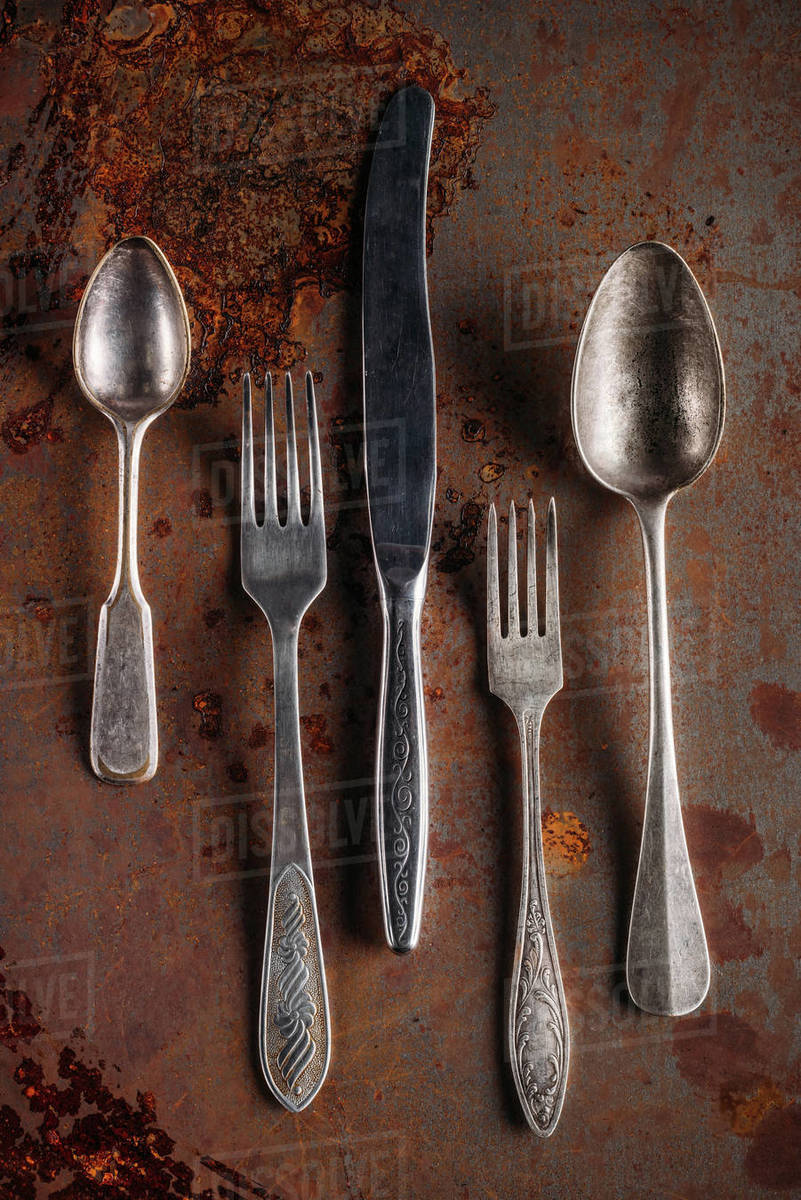 Vintage spoons and forks with knife on rusted background - Stock Photo