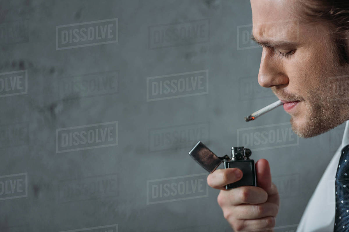 Closeup portrait of man smoking cigarette in front of concrete wall