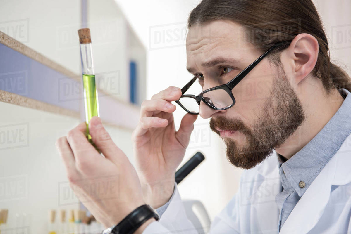 Young male scientist looking at chemical sample in test tube - Stock Photo  - Dissolve