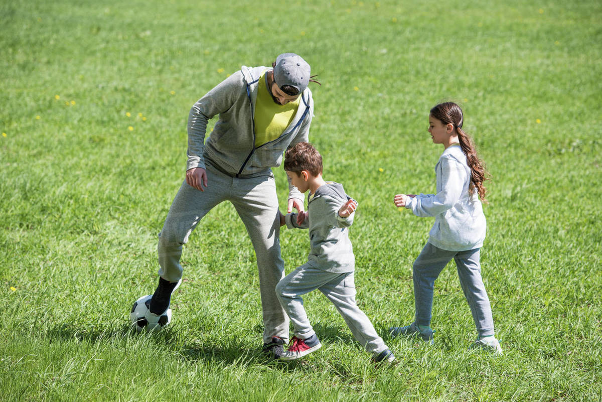 Father playing football with daughter and son in park Stock Photo