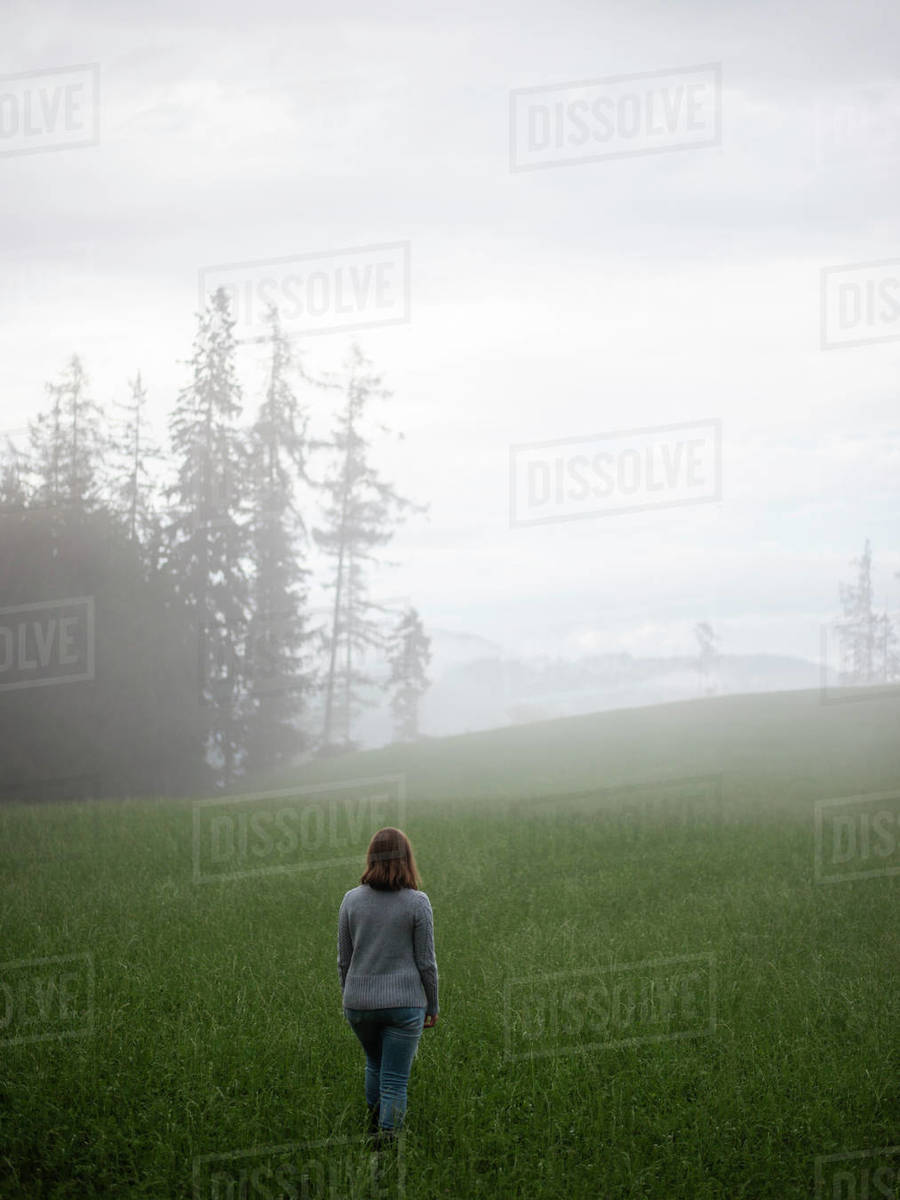 Woman standing in field looking away in fog Royalty-free stock photo