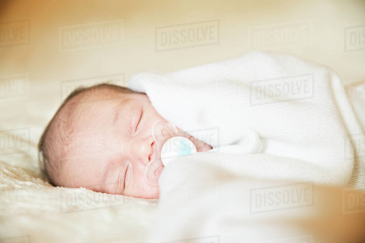 Closeup of newborn baby boy sleeping with dummy in mouth Stock Photo