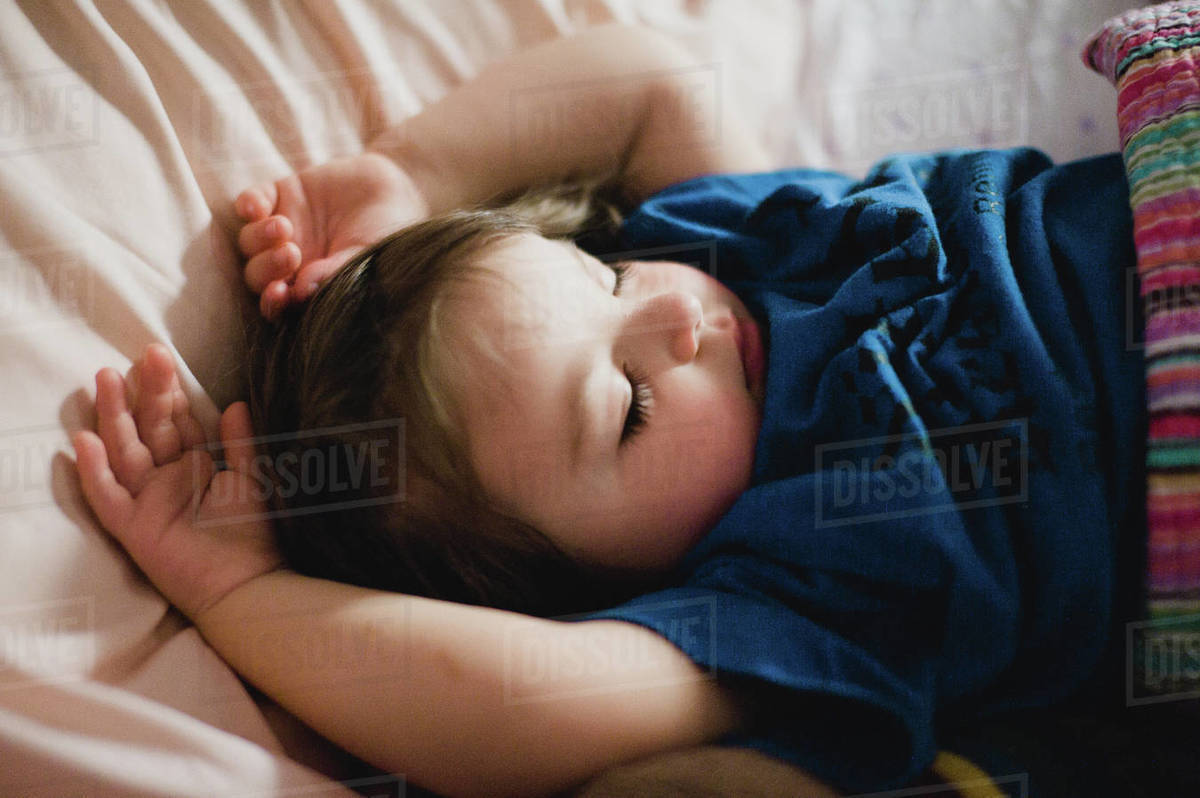 Closeup of a girl sleeping with her arms above her head Stock Photo