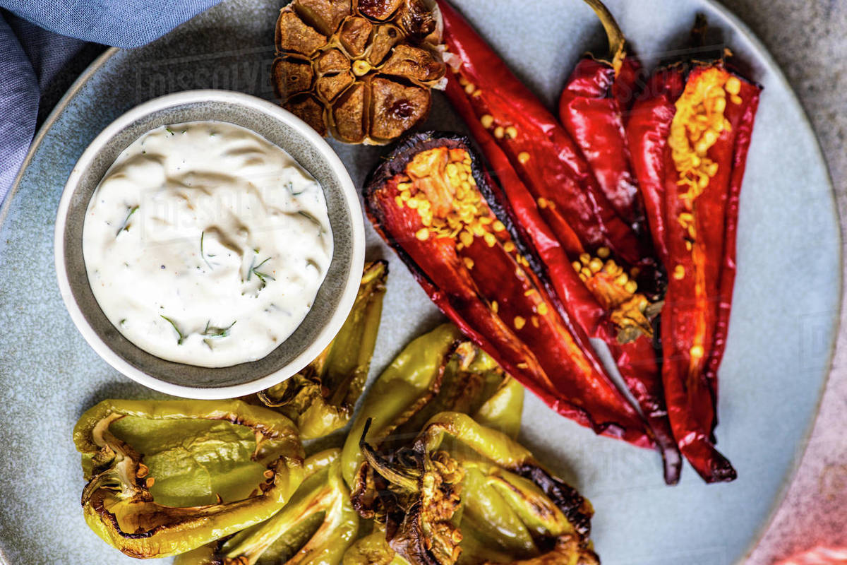 Overhead view of a plate of roasted peppers, garlic and sour cream