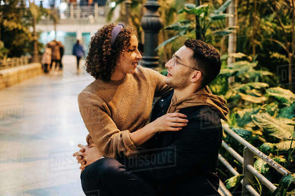 Side view of young man and woman hugging and looking at each other ...