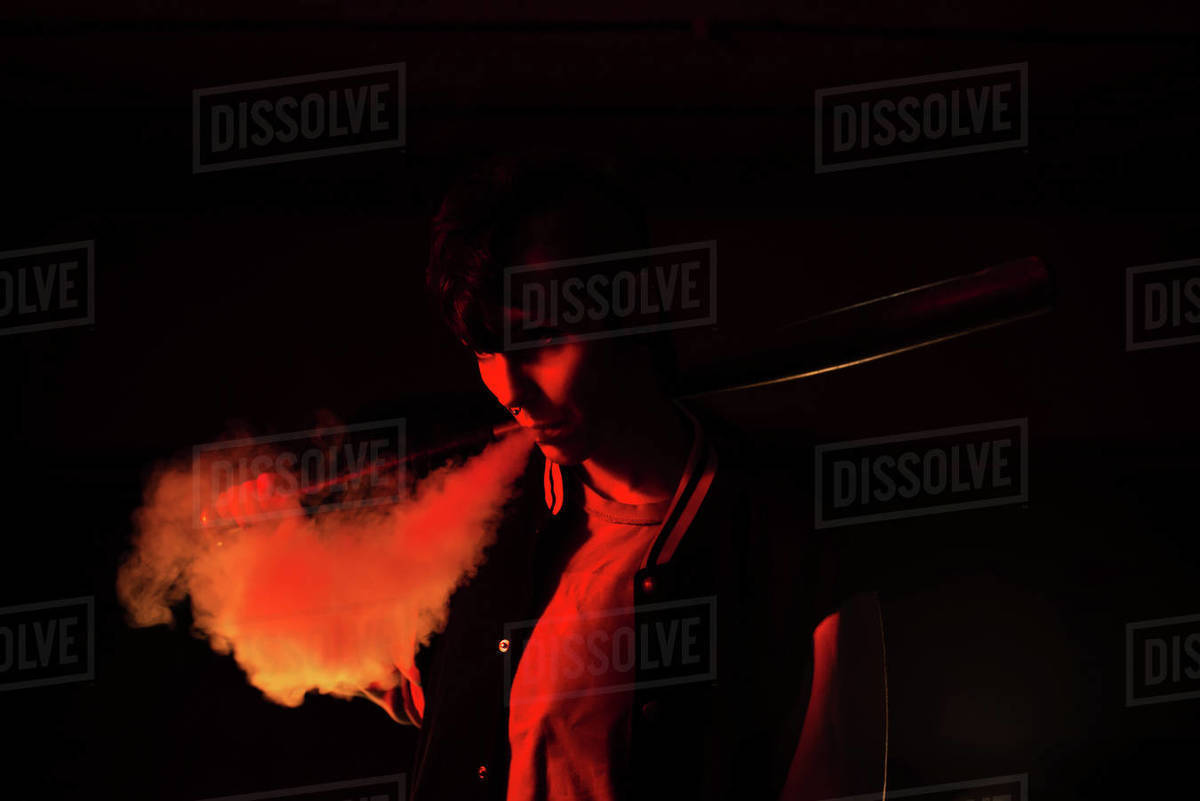 Contemporary female in bomber jacket holding a black baseball bat on