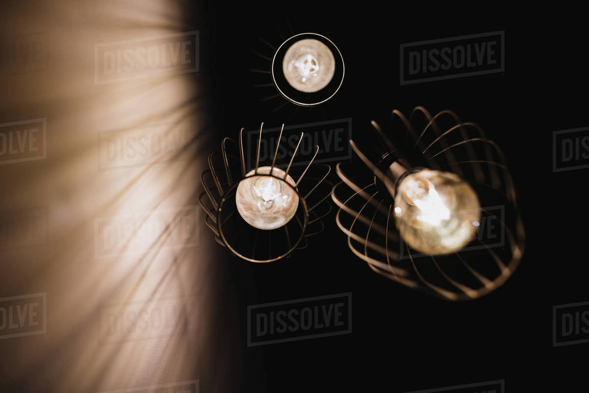 From below stylish lanterns with glowing light bulbs hanging from