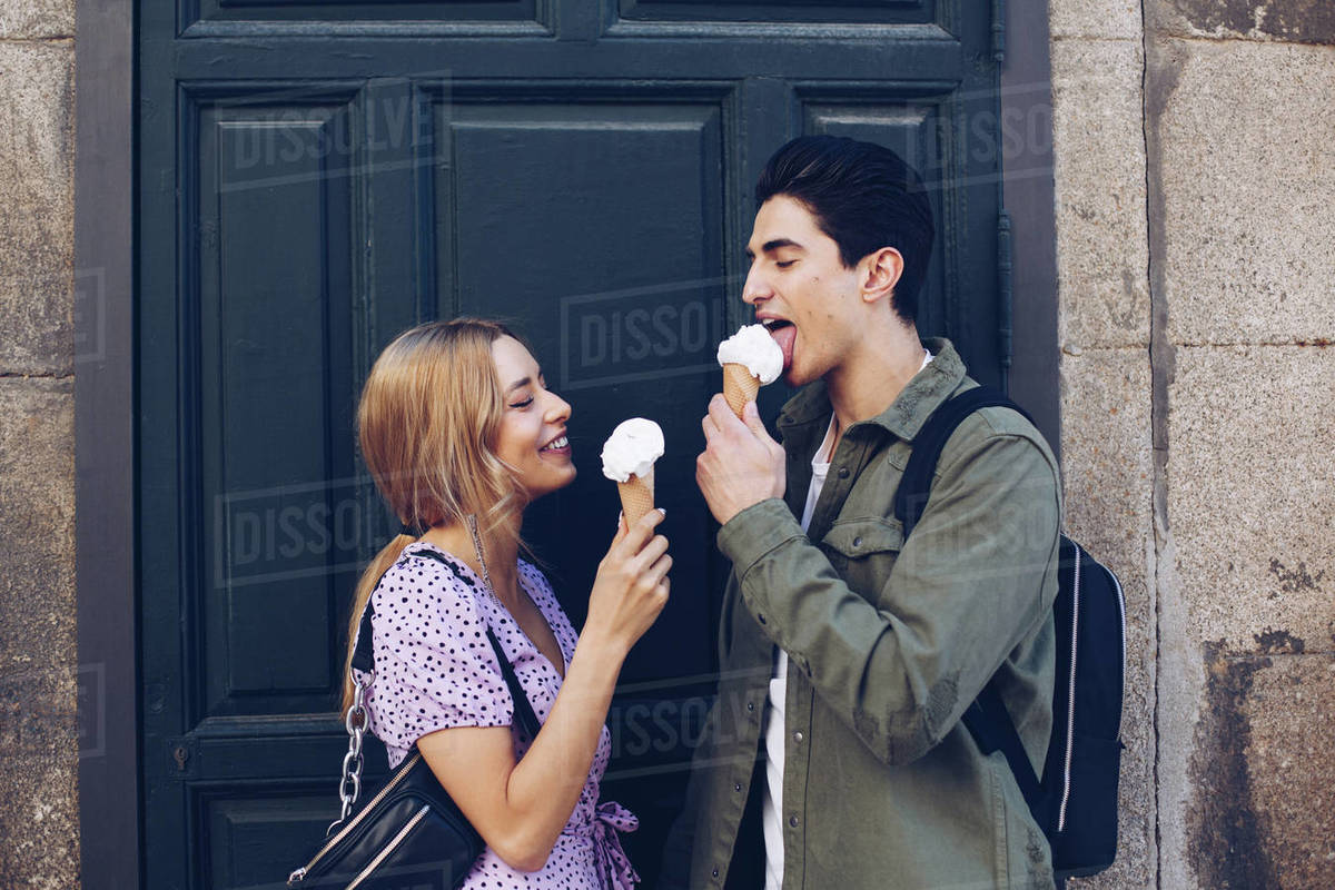 Cheerful young attractive woman and boyfriend eating of ice