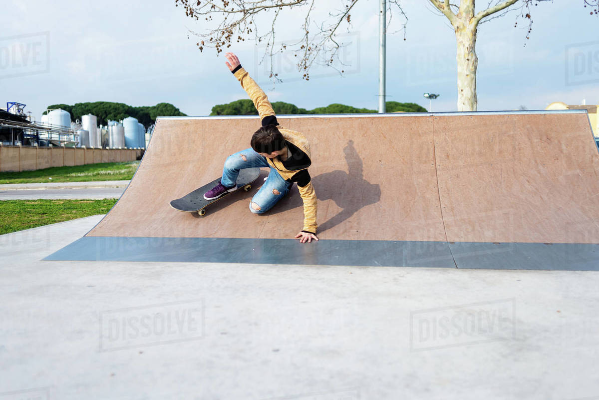 Teenage boy performing trick on skateboard on ramp while practicing tricks on sunny day Royalty-free stock photo