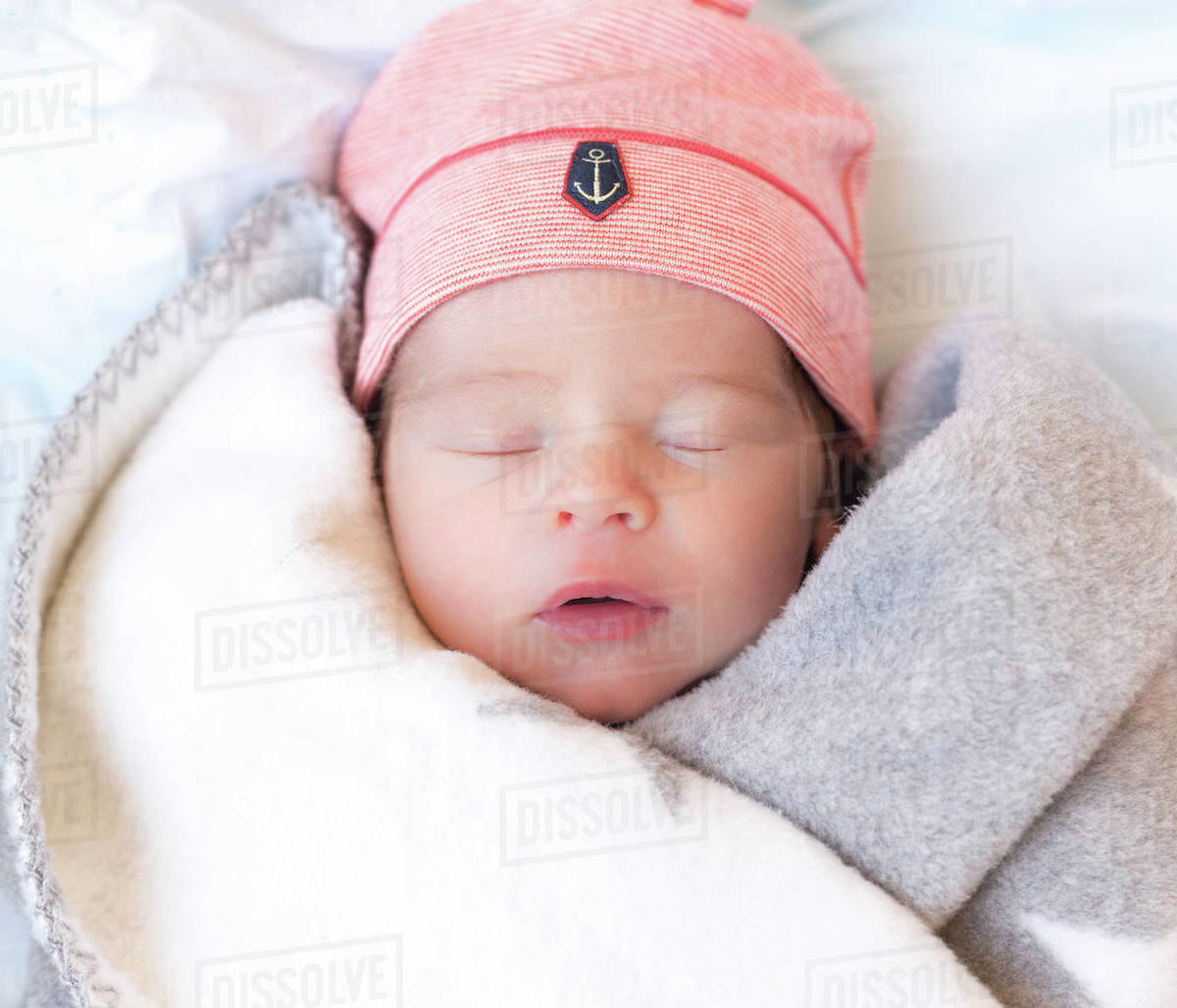 Cute baby in blanket and hat sleeping on bed Stock Photo Dissolve