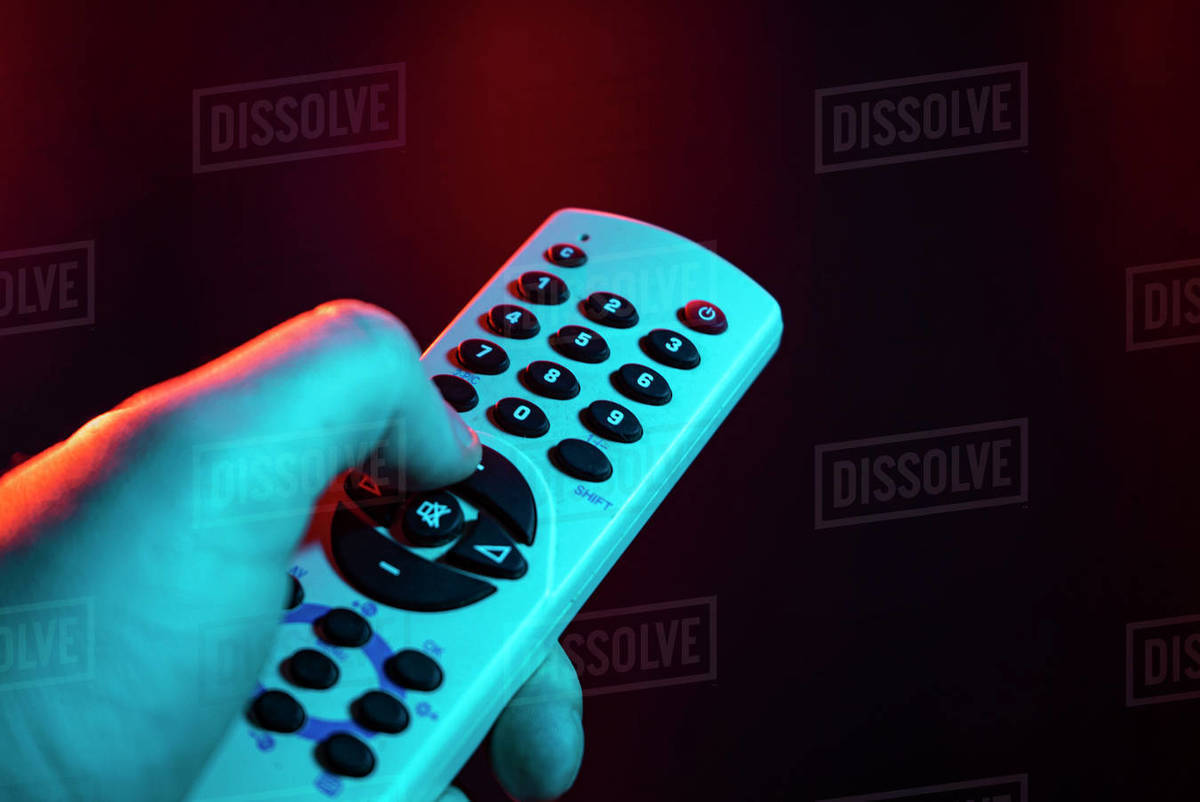 Hold remote control in hand and zap. Male hand is holding TV remote