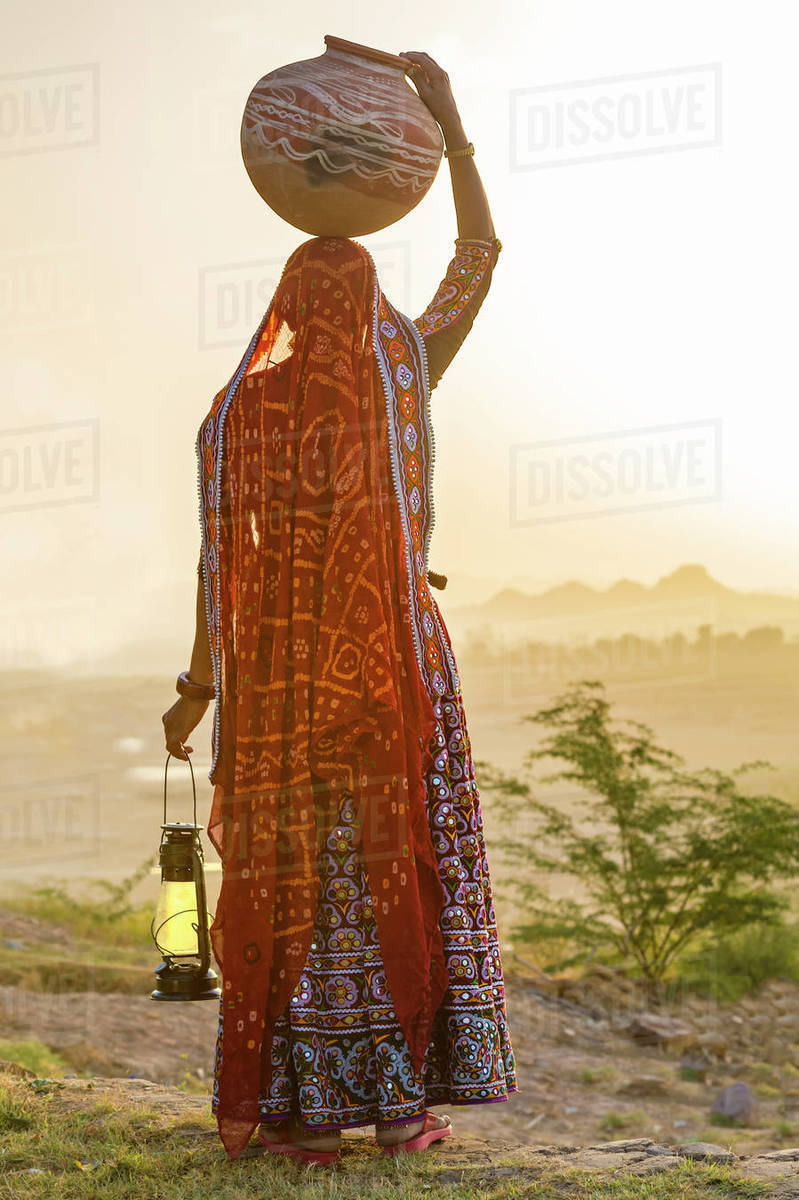 Ahir Woman in traditional colorful cloth carrying water in a clay jug