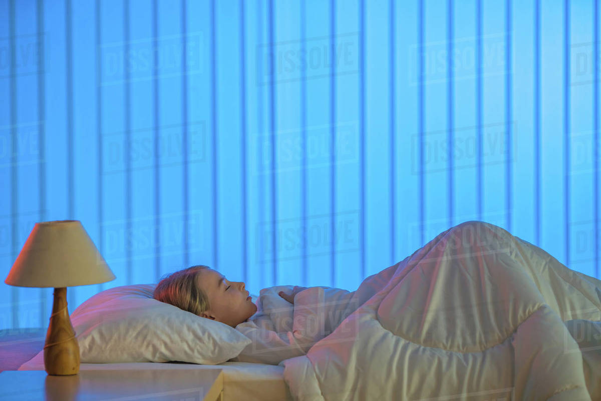 The cute girl sleeping on the bed. Evening night time Stock Photo Dissolve