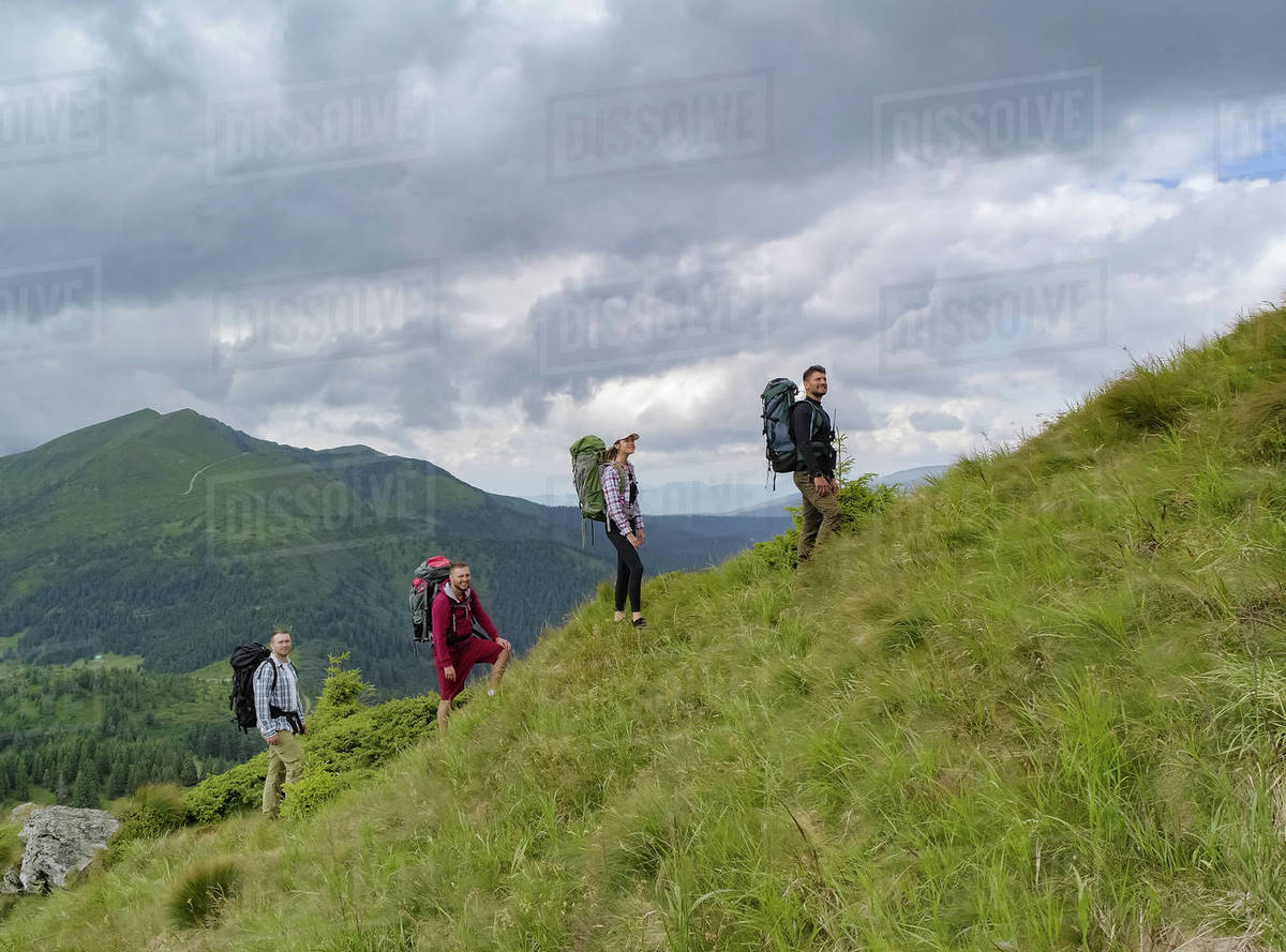 The four people with backpacks walking on the mountain Royalty-free stock photo