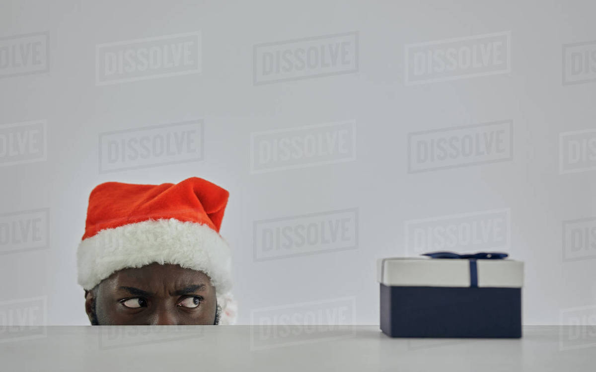 The african man in the santa hat watching from the table with a gift Royalty-free stock photo