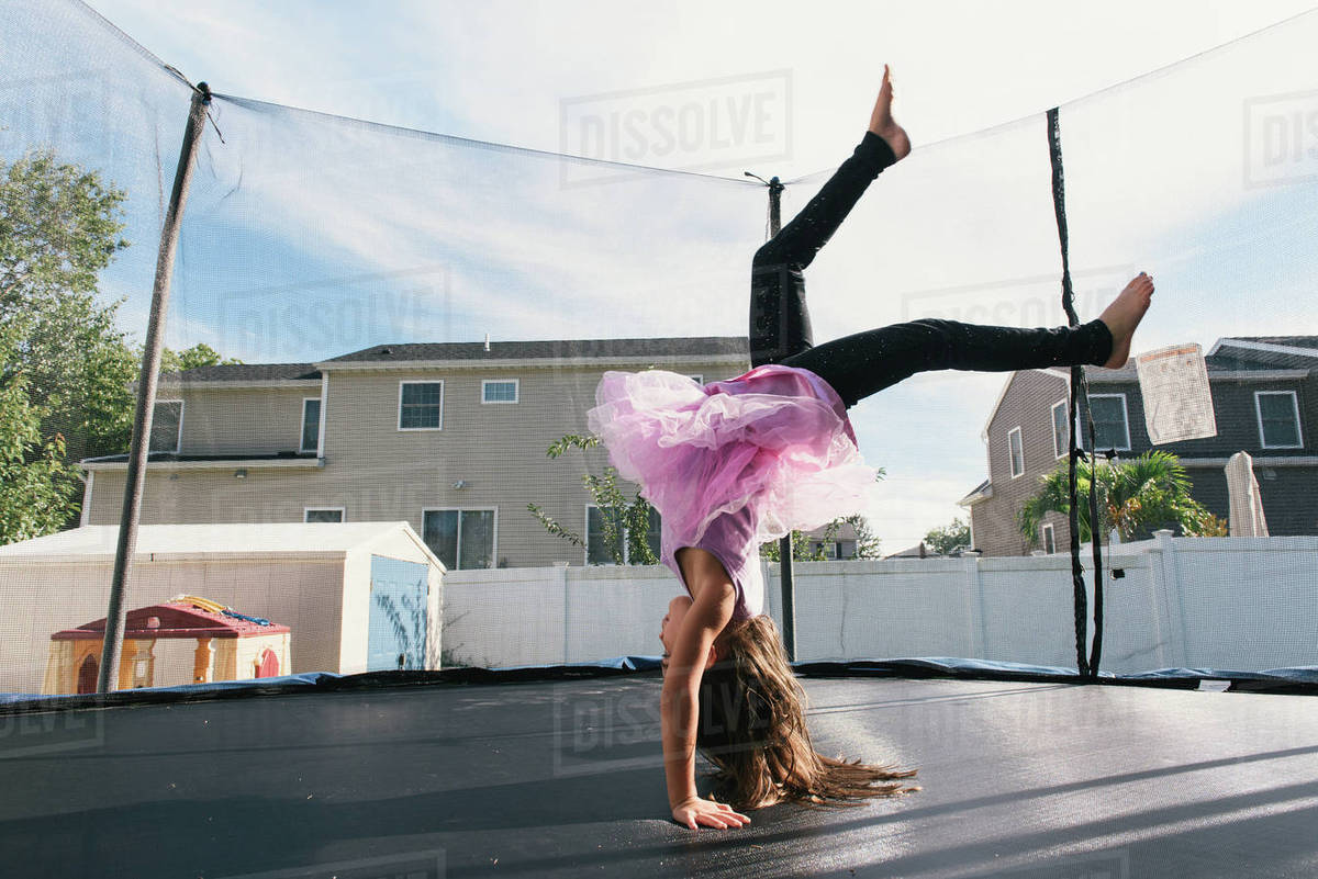 Girl upside down doing handstand on trampoline Stock Photo Dissolve